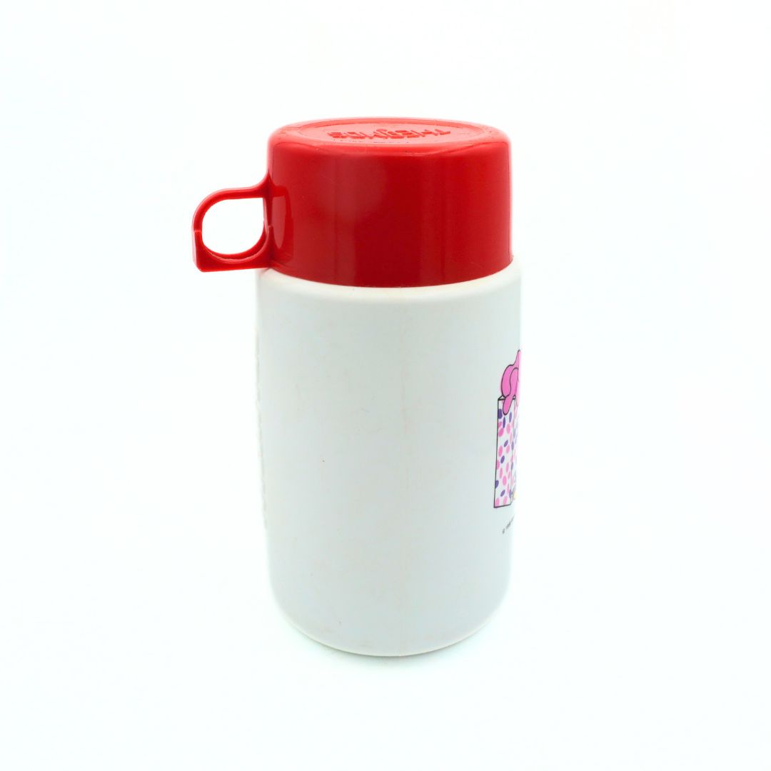 Side on photo of a 1990 Barbie thermos with a red lid