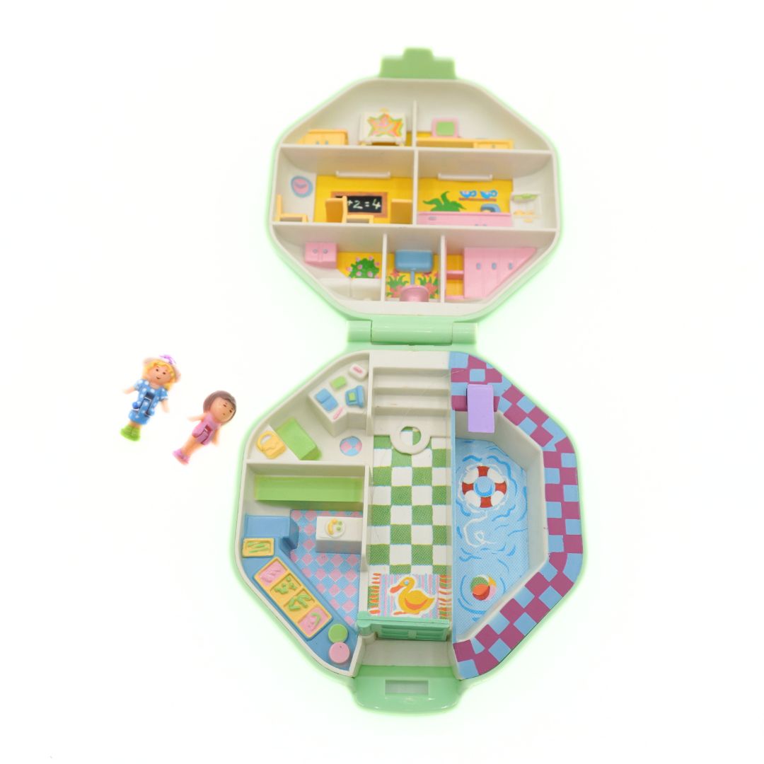 Toy dollhouse with various rooms and furniture on a white background