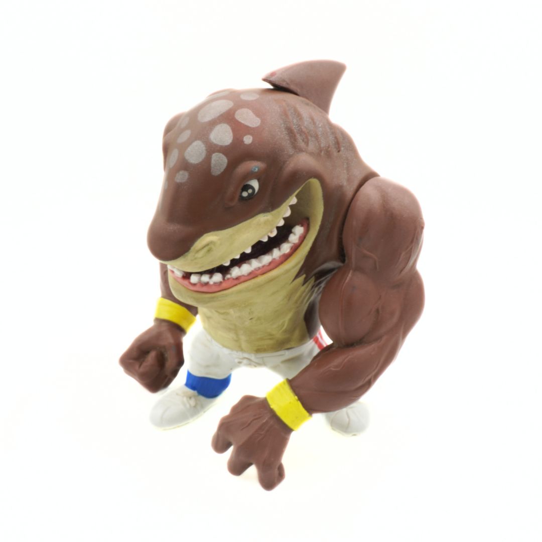 Toy figure of a shark with a muscular build on a white background