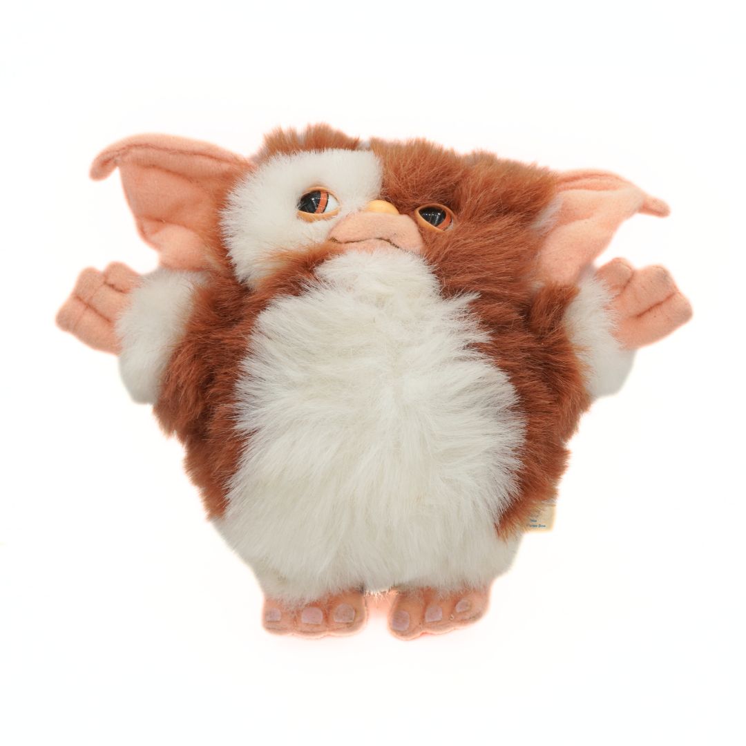 Plush toy resembling a creature with large ears and white fur on a white background