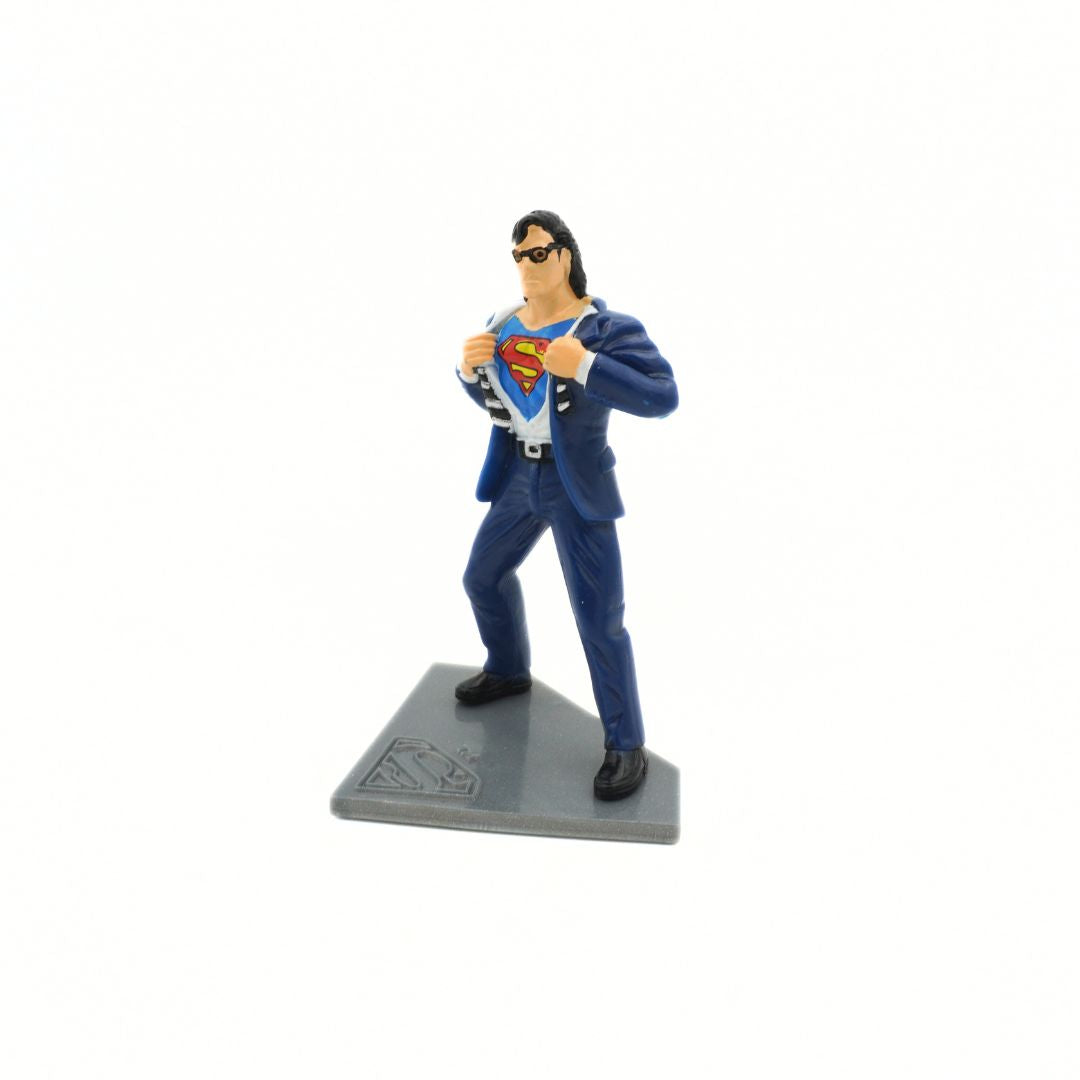 A vintage 90s Clark Kent transforming into Superman figurine on a grey stand