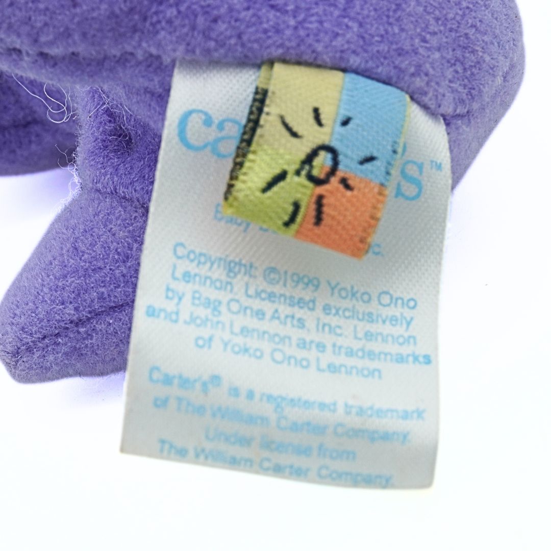 Close-up of a purple plush toy with a label featuring the name 'Carter's'.