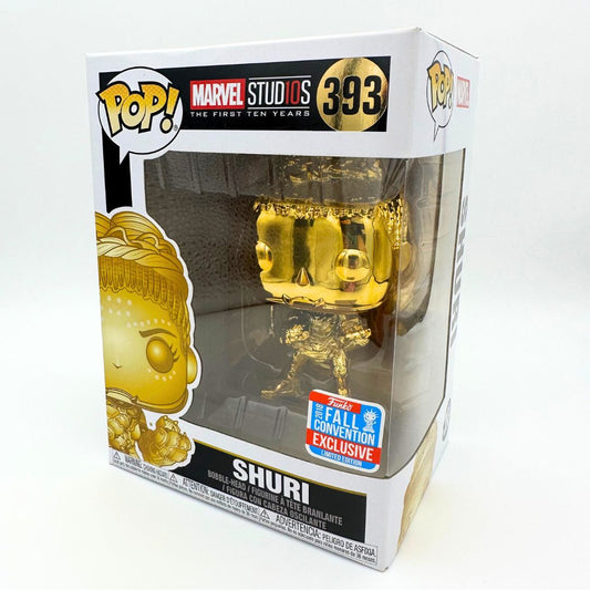 A photo of the Shuri Black Panter393 Funko Pop in a limited gold colourway. She is inside her original box and the figure can be seen through the plastic bubble