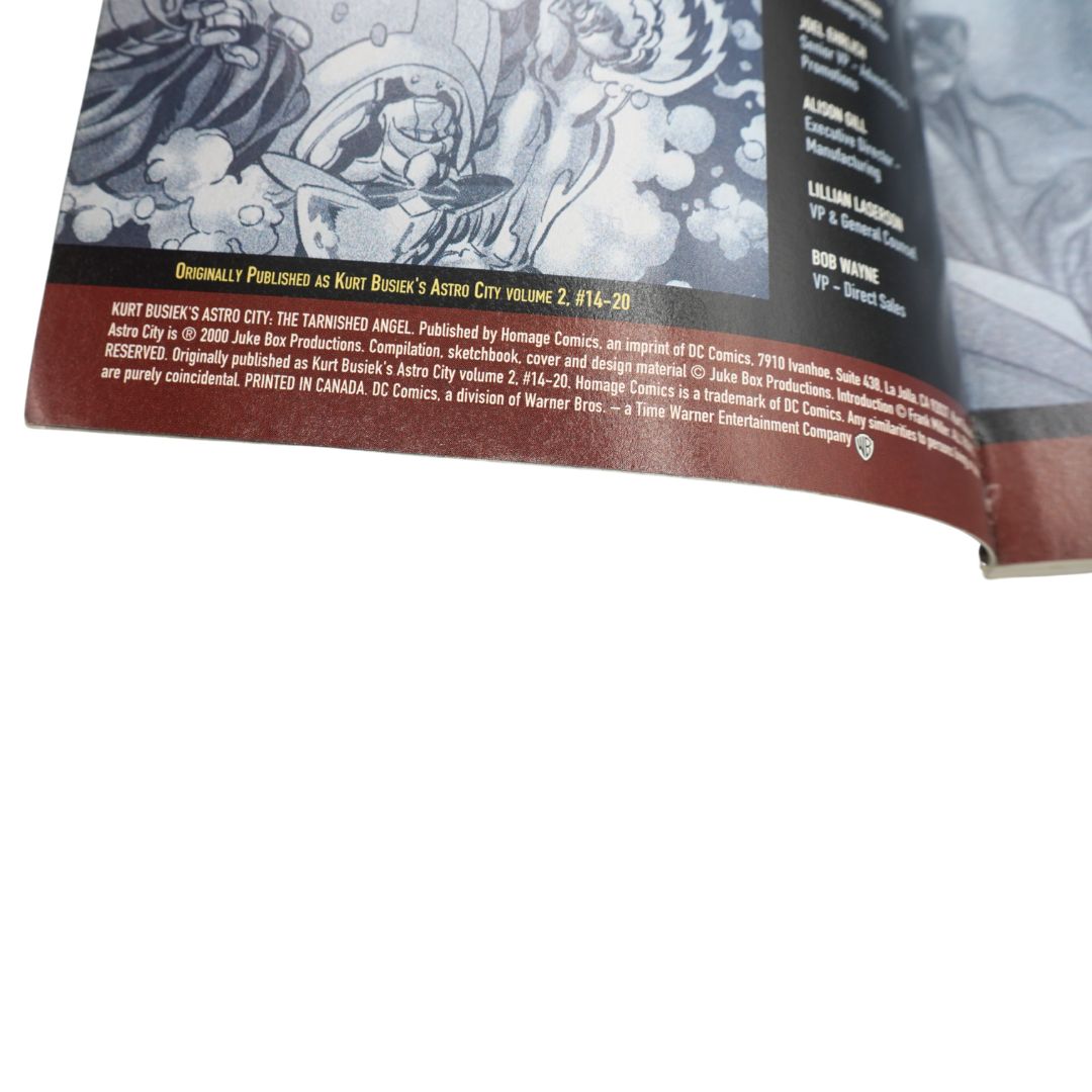 A close-up of a printed comic book or booklet page showing illustrated artwork in black and white with a dark red band containing publication text, photographed against a white background.