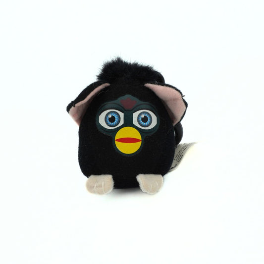 Black plush toy with blue eyes and a yellow beak on a white background