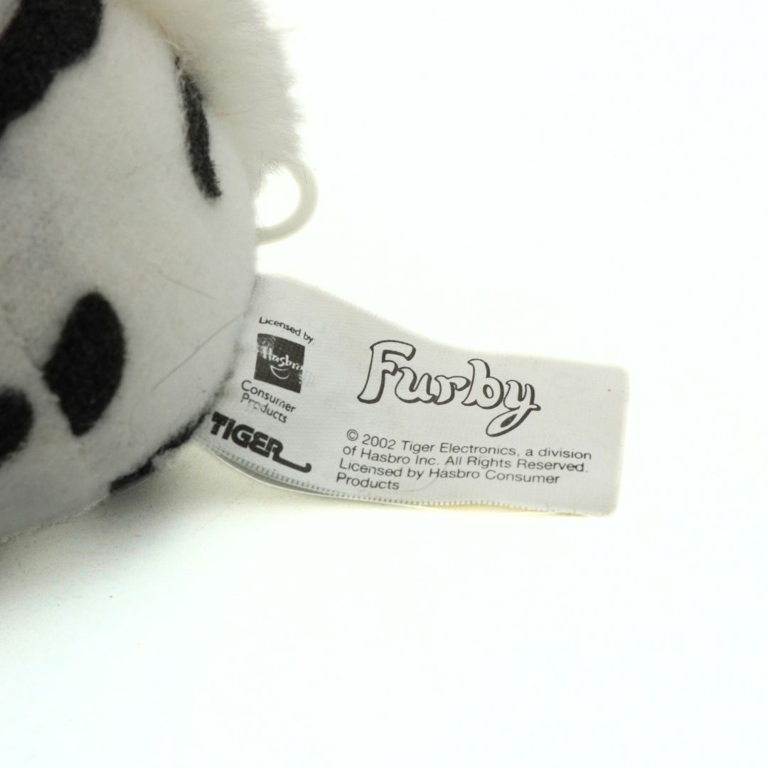 Close-up of a Furby toy with a visible label on a white background