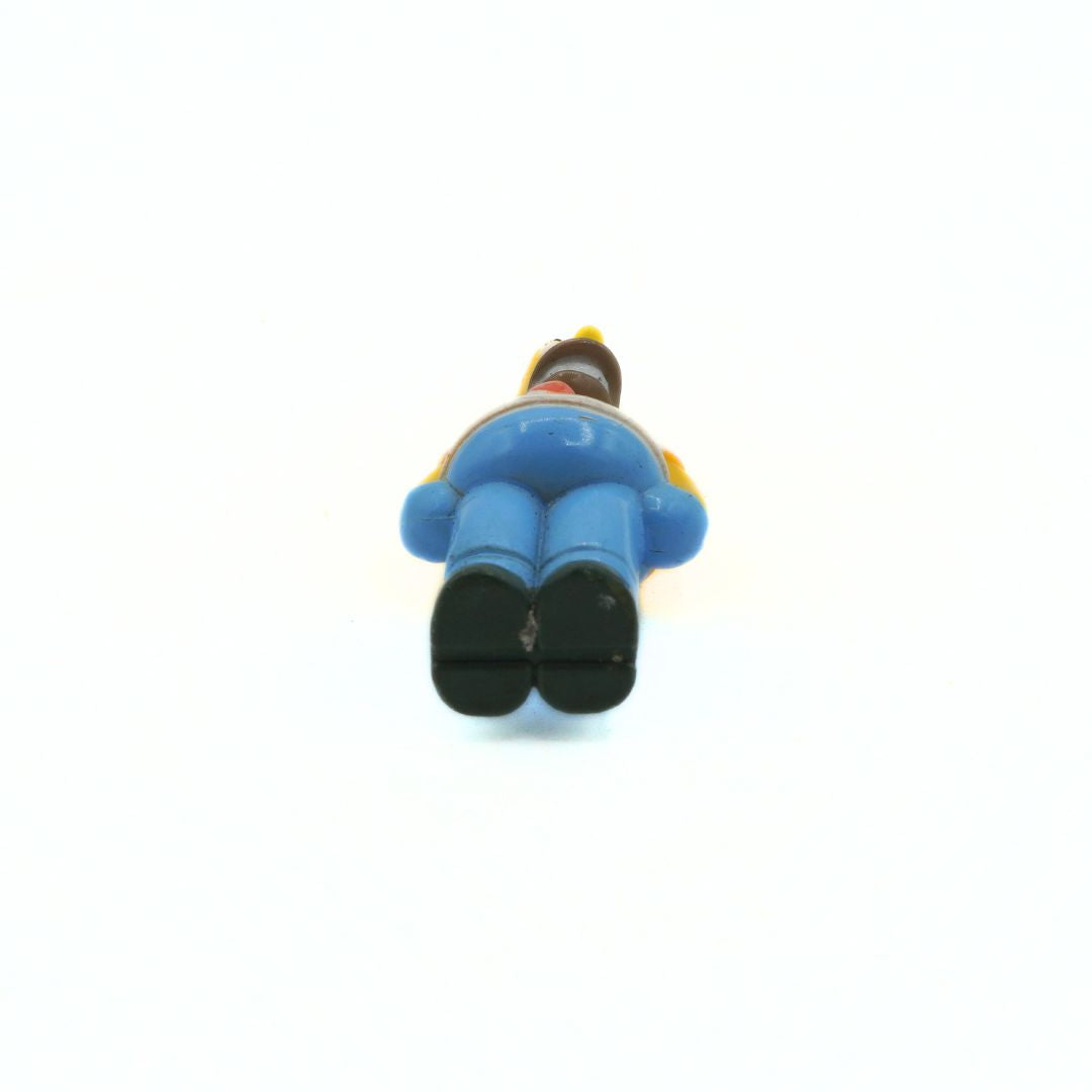 Small figurine of a character in blue pants and black shoes on a white background