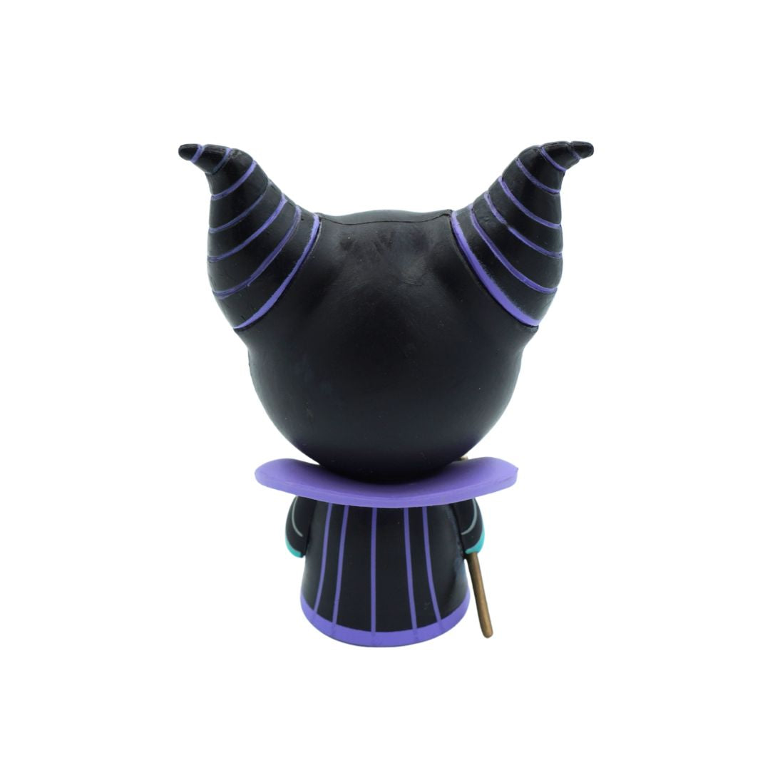 A stylized collectible figurine of Maleficent from Disney's Sleeping Beauty, shown from the back. The figure features a large black round head with two curved horns outlined in purple, a purple collar, and a purple-trimmed striped body, holding a small brown staff.