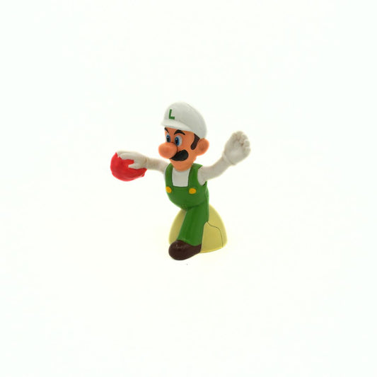 Toy figure of Luigi in green overalls and white cap holding a red object on a white background