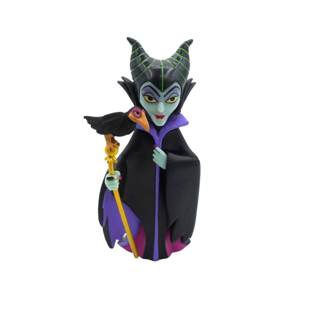 A collectible figurine of Disney's Maleficent from Sleeping Beauty, standing on a white background. She is depicted with her signature black and purple gown, green horns, and holding a gold staff.