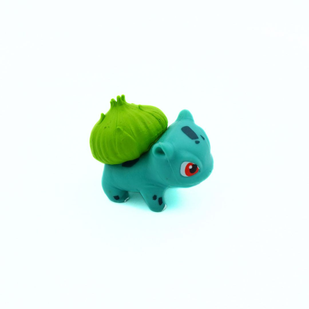 Small blue creature figurine with a green object on its back against a white background