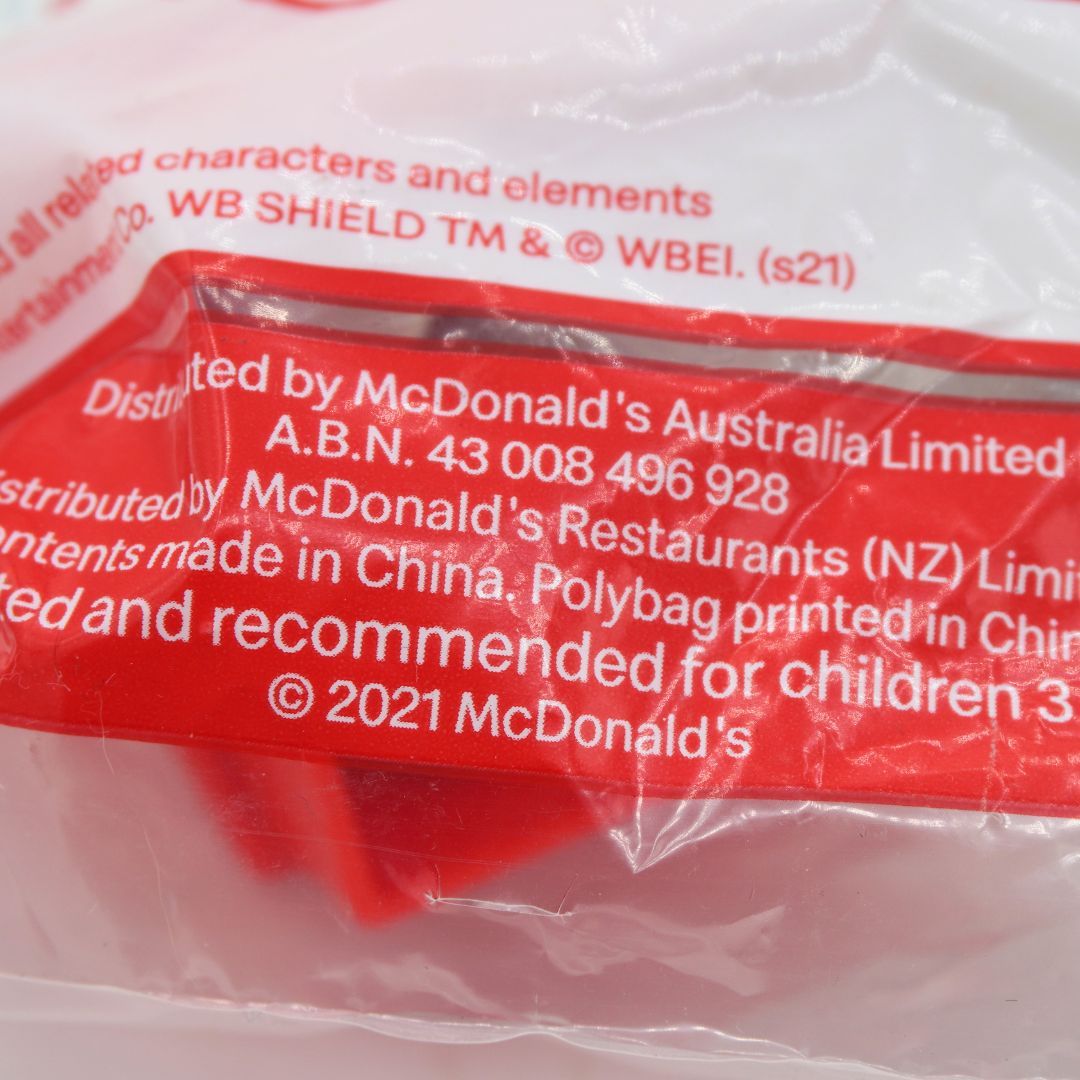 Close-up of a McDonald's product in a clear plastic bag with a red printed label. Visible text includes 'Distributed by McDonald's Australia Limited' and '© 2021 McDonald's'.