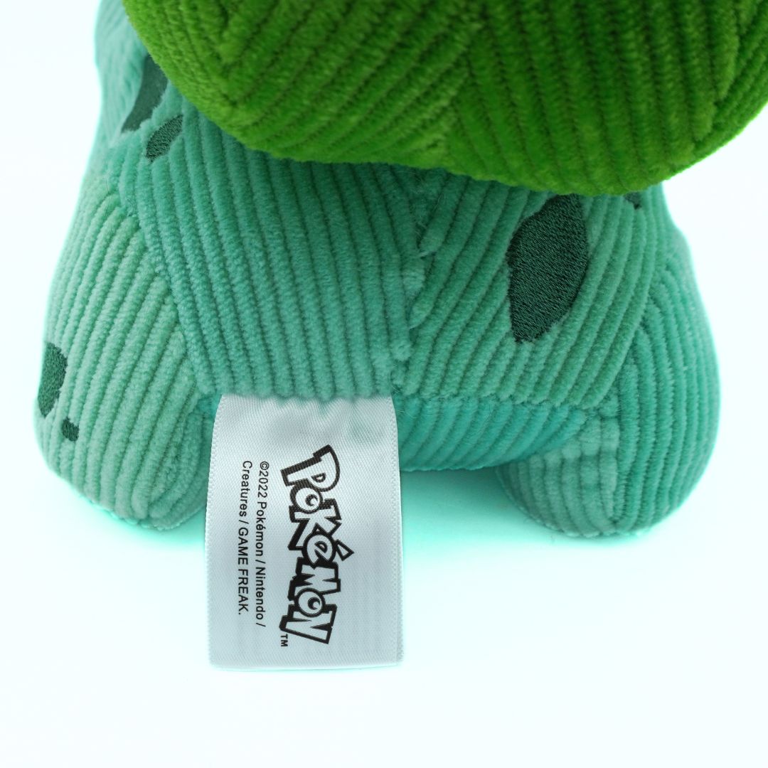 Green plush toy with a visible Pokemon tag on a white background