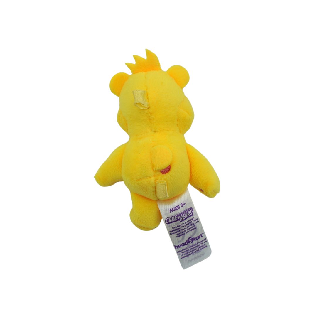 A yellow plush toy shaped like a bear with a small tuft of hair, shown from the back with a white product tag attached, on a plain white background.