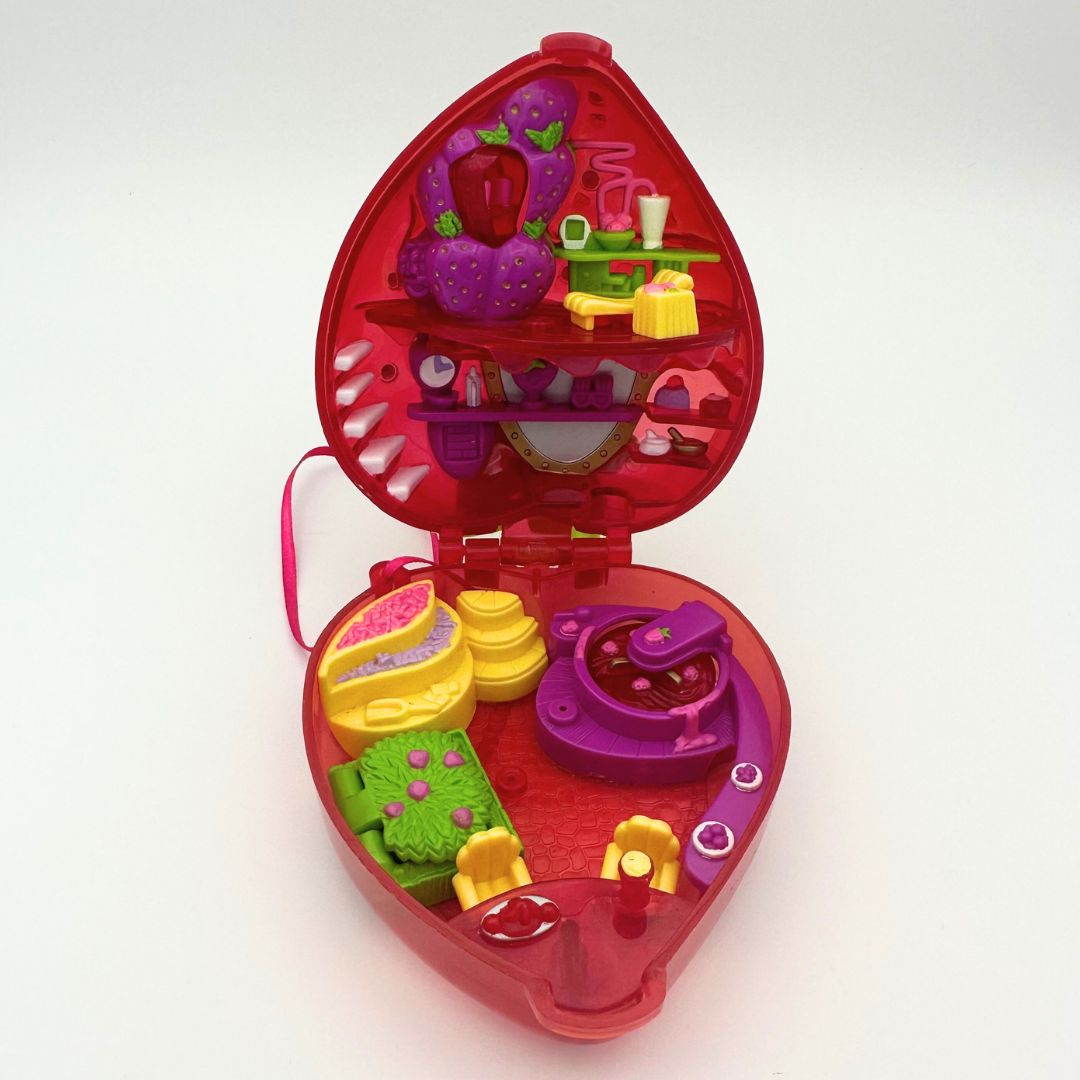 A front on photo of the Strawberry Polly Pocket from the 90s, opened to display the interior