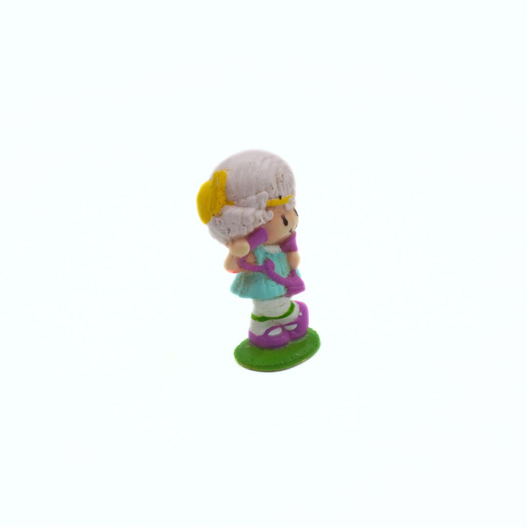 Small figurine of a girl with a yellow flower in her hair on a white background