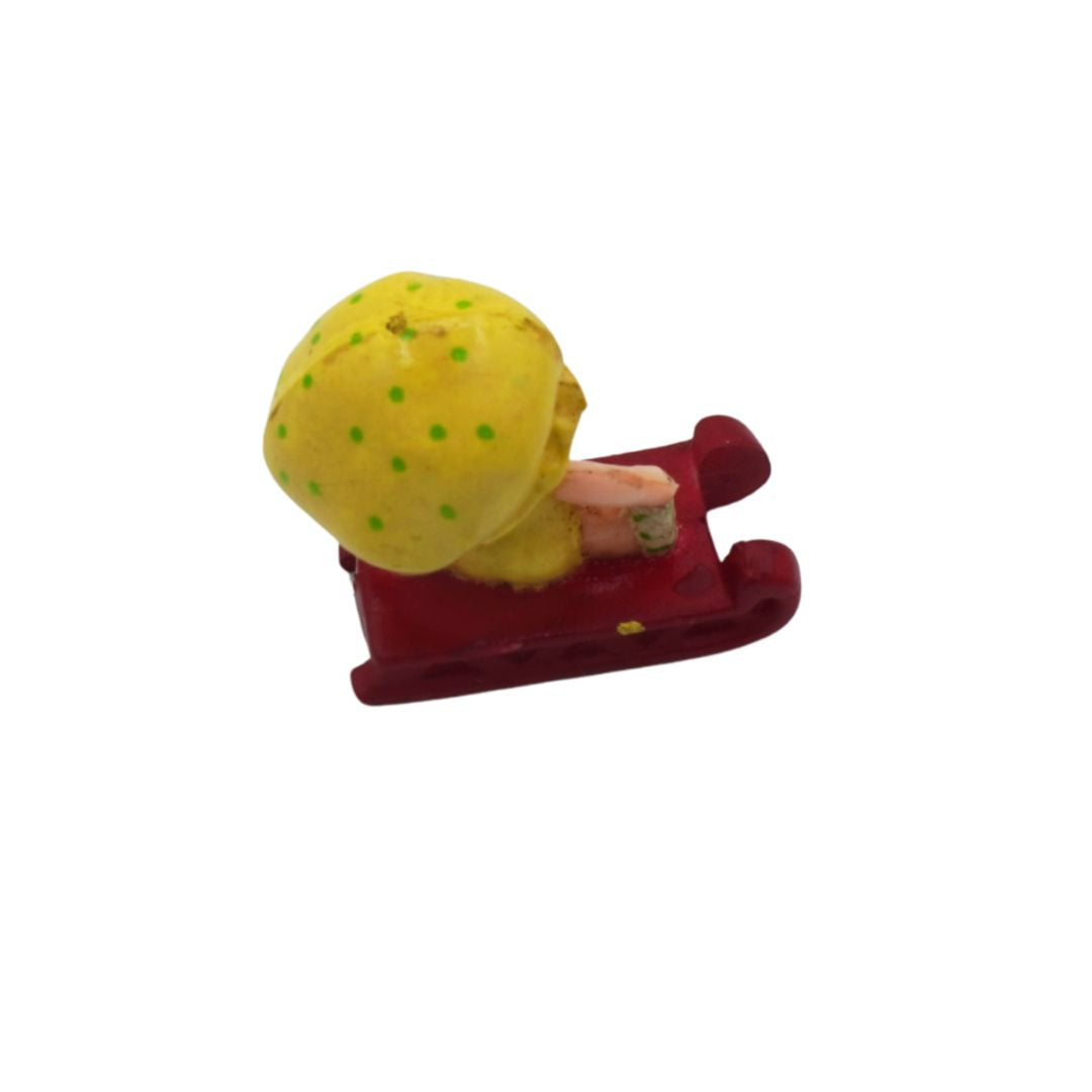 Toy figure of a character with a yellow polka-dotted head and red body on a white background