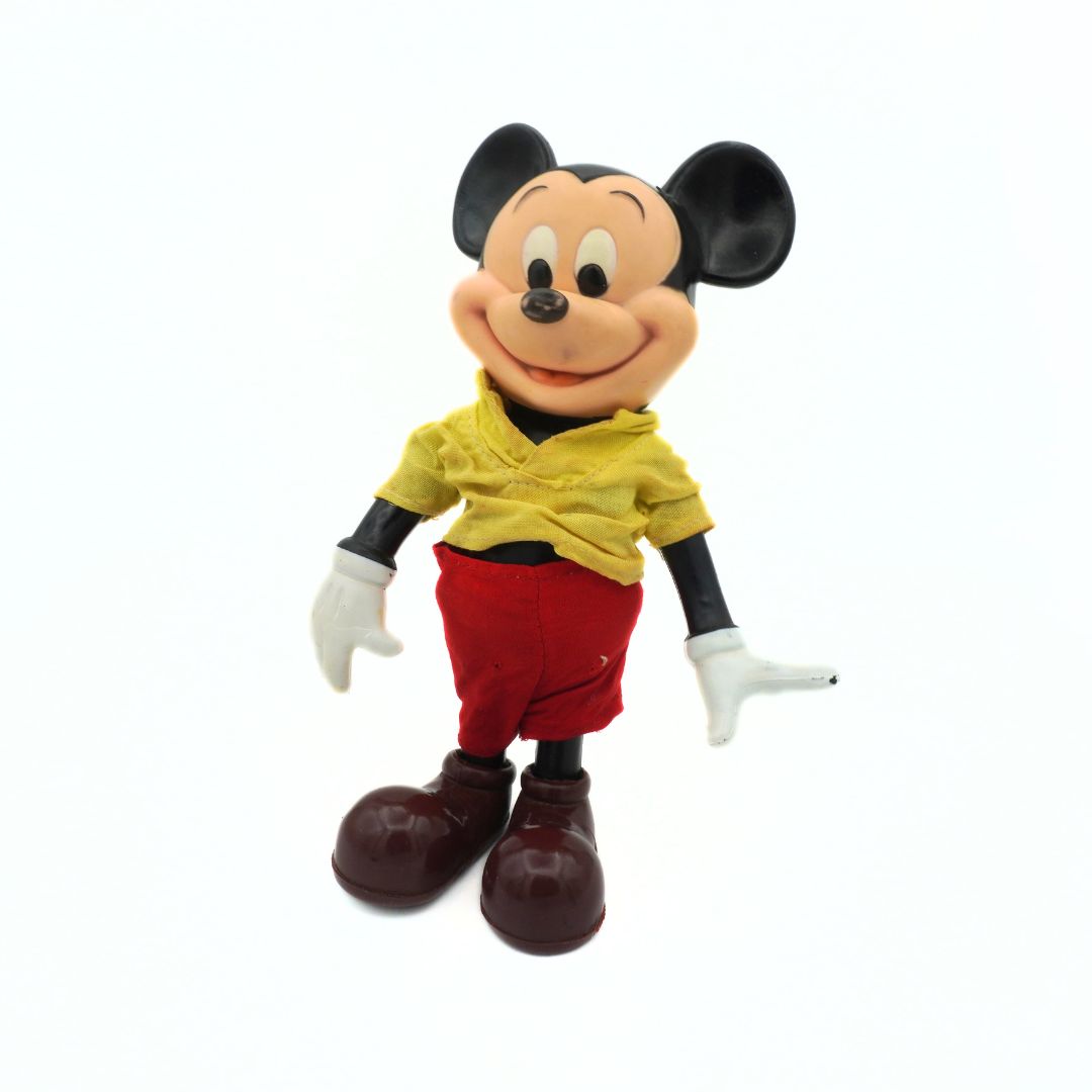 Mickey Mouse figurine wearing a yellow shirt and red pants on a white background