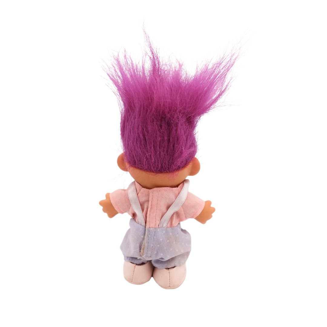 The back of a fuchsia hair colour Troll doll released in the 80s, wearing shoes, overalls and a shirt.