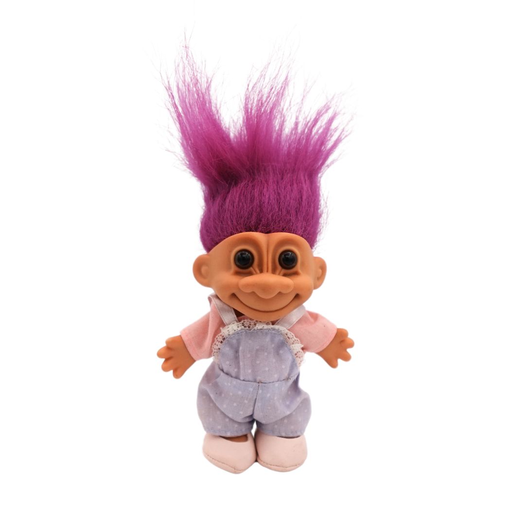 A fuchsia hair colour Troll doll released in the 80s, wearing shoes, overalls and a shirt.