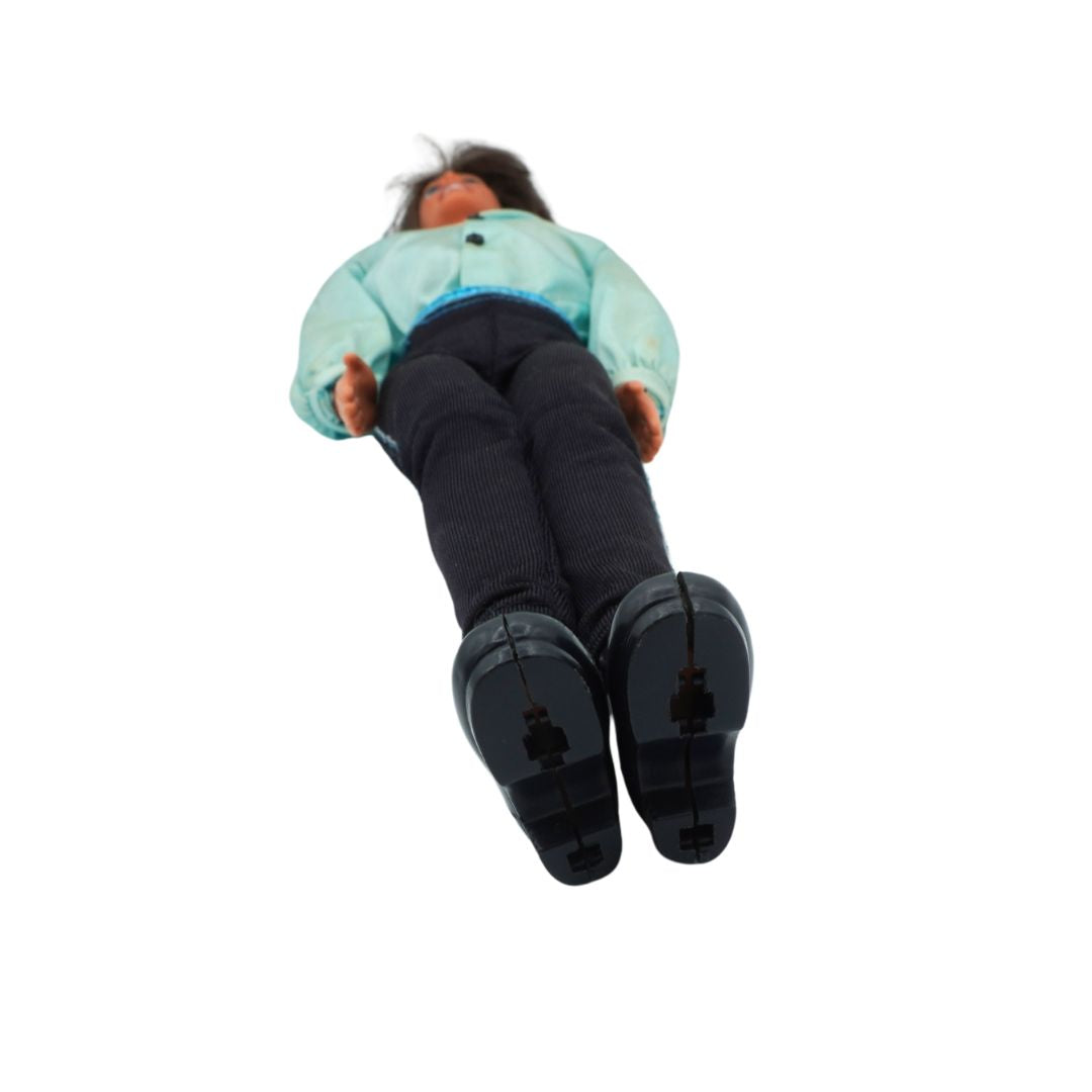 Ken doll wearing a light blue jacket and dark pants on a white background