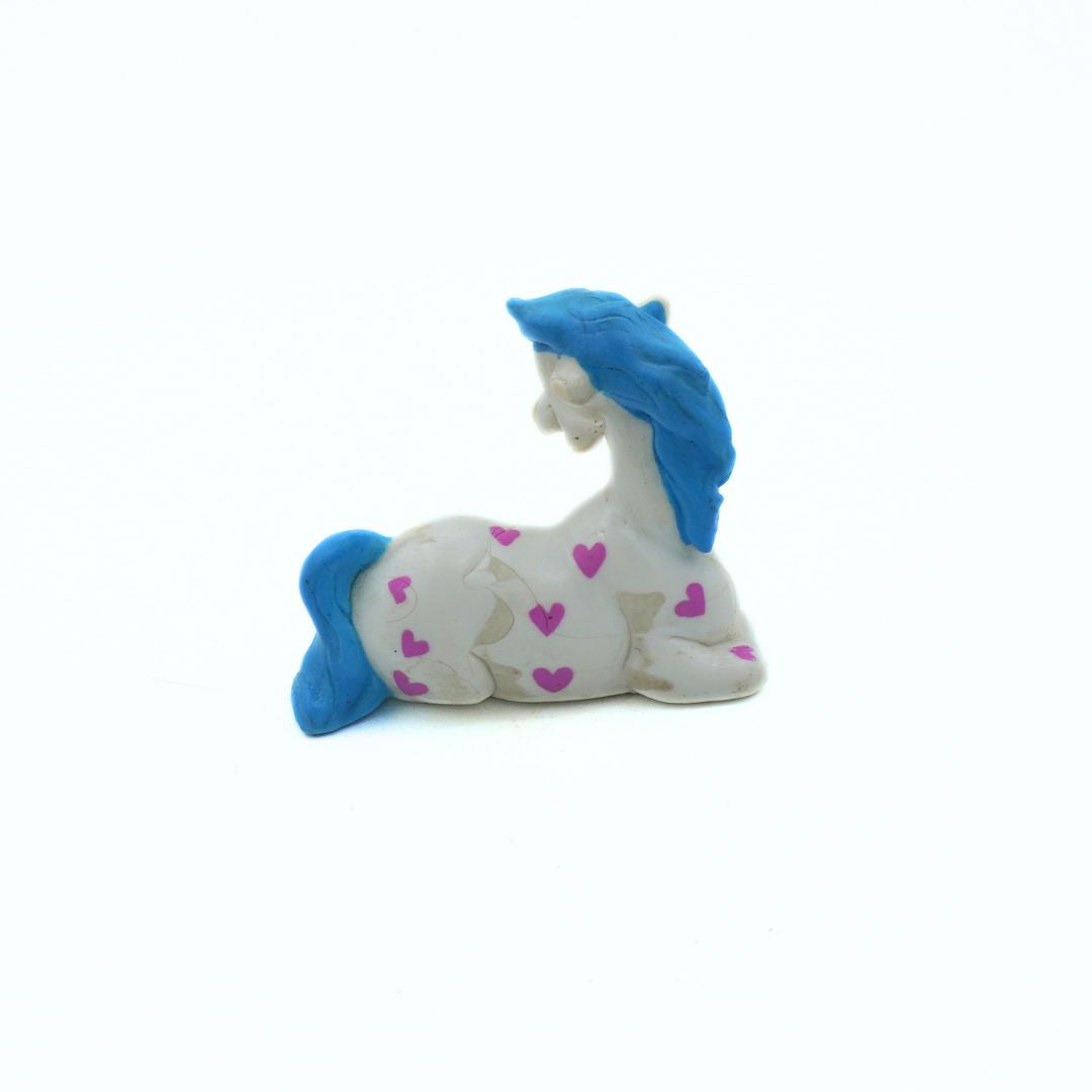 Plastic toy horse with blue mane and pink heart patterns on a white background