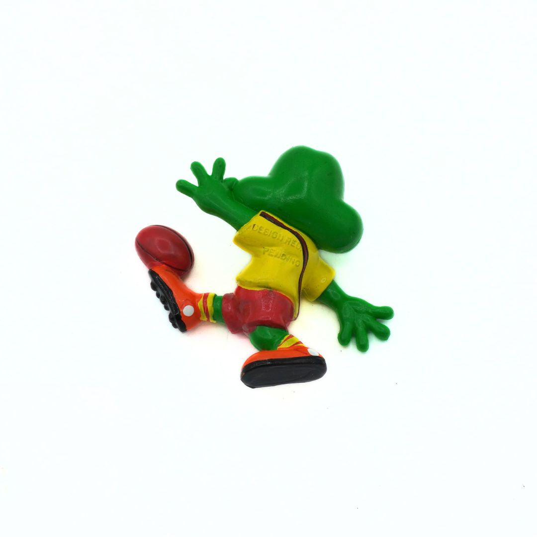 Colorful frog figurine kicking a soccer ball on a white background