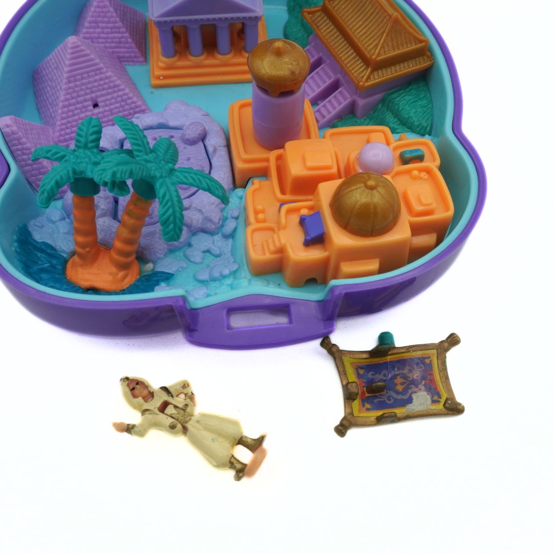 Toy set with a sandpit, palm trees, and various toys on a white background