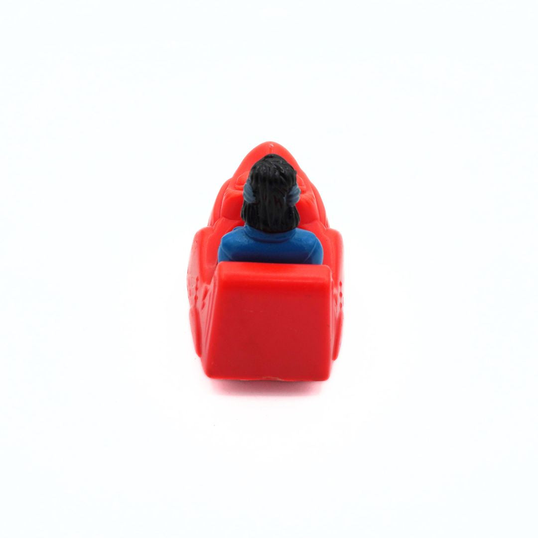 A small red toy vehicle with a miniature figure seated inside, shown from behind on a plain white background.