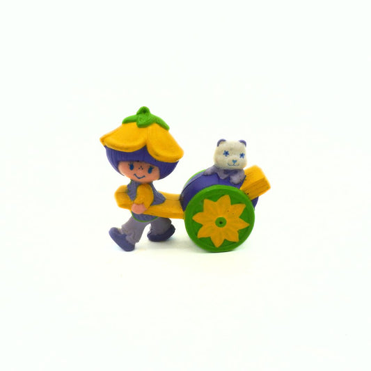 Toy figure of a character with a flower-shaped hat and cart, featuring a small animal, on a white background.