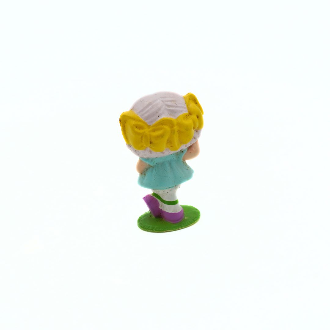 Small figurine of a girl with yellow flowers in her hair on a white background
