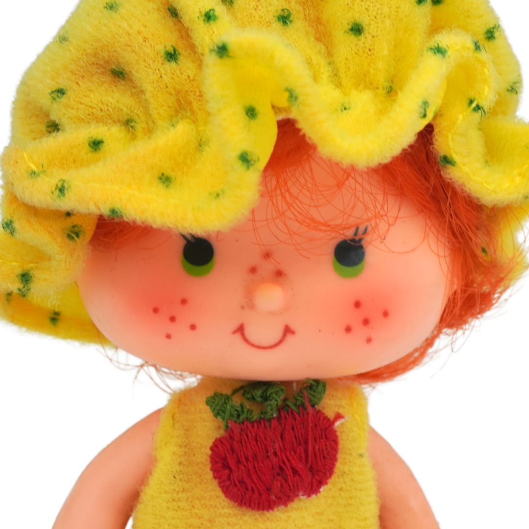Toy figure with a yellow outfit and flower hat on a white background