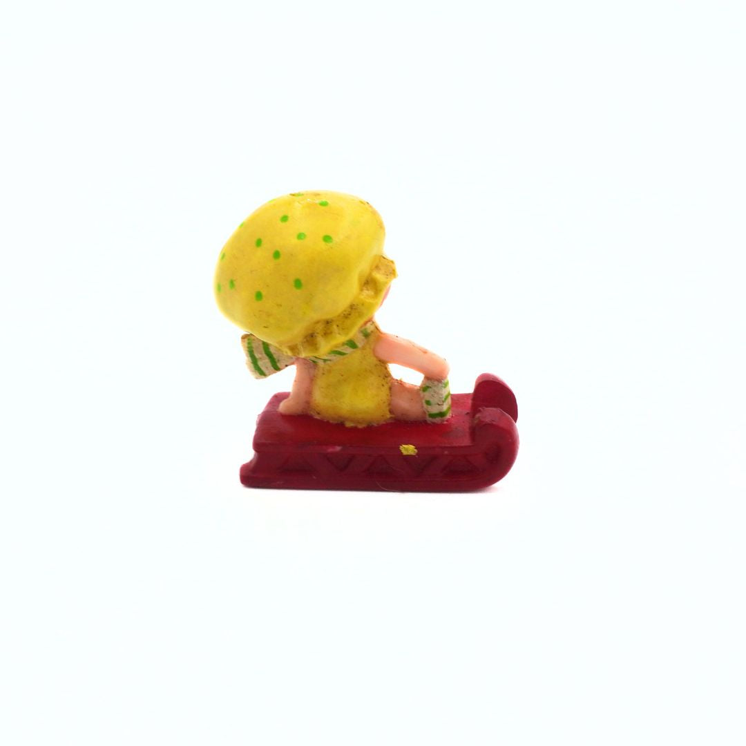 Small figurine of a character with a yellow hat and red base on a white background