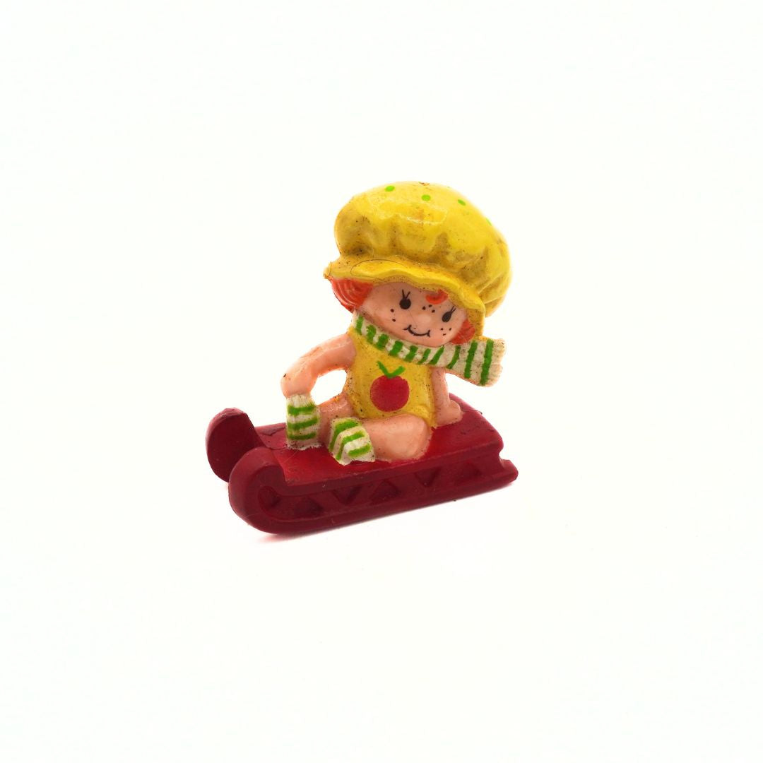 Toy figure of a character with a yellow hat and red sled on a white background
