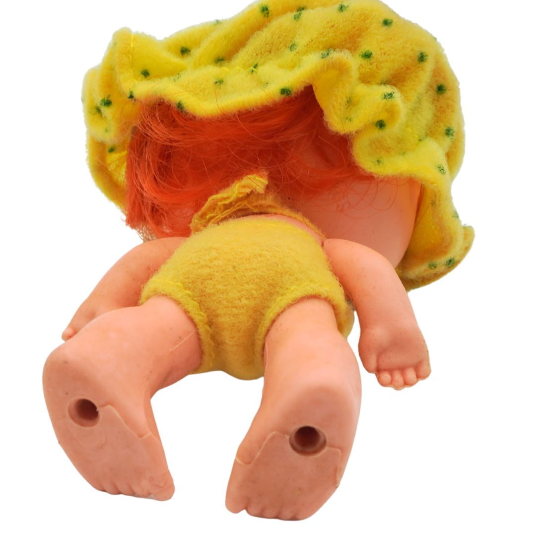 Toy figure with a yellow outfit and red hair on a white background