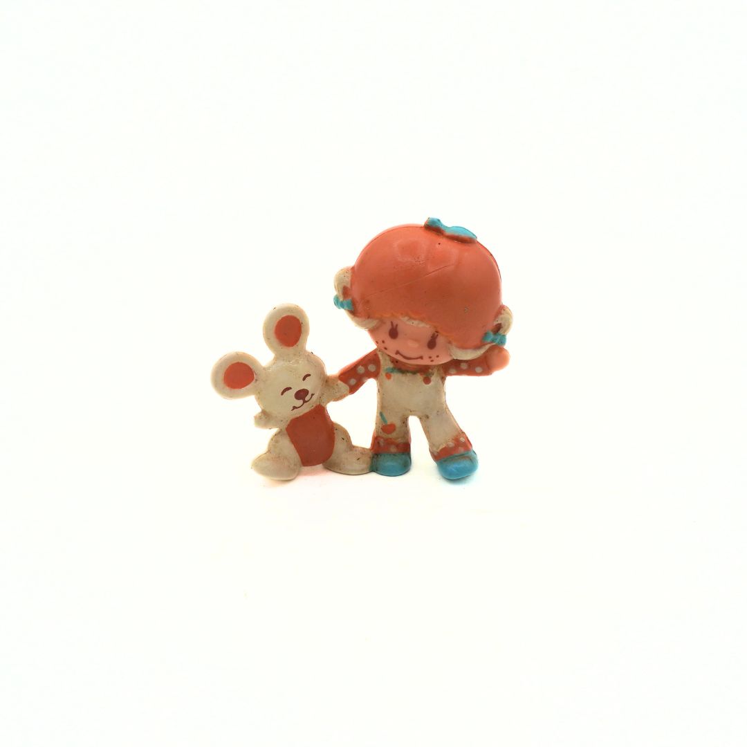 Two small figurines, one resembling a bunny and the other a character with an orange head and blue shoes, on a white background.