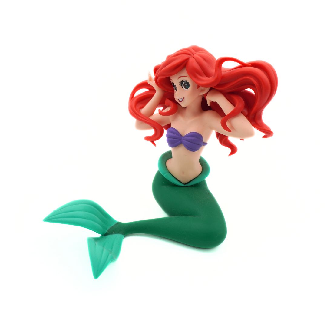 A small Ariel mermaid figurine with long red hair, a purple top, and a green tail, posed against a plain white background.