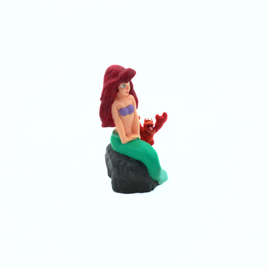 Mermaid figurine with red hair and green tail on a white background