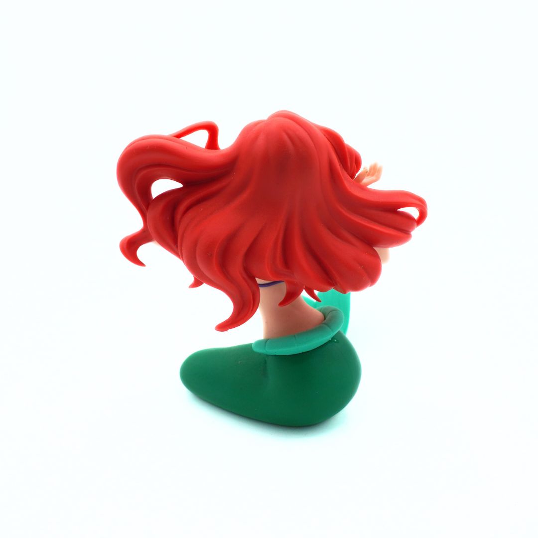 A stylized red-haired female character bust or figure head with bright red hair, a pale skin-toned neck, and a green top, photographed against a plain white background.