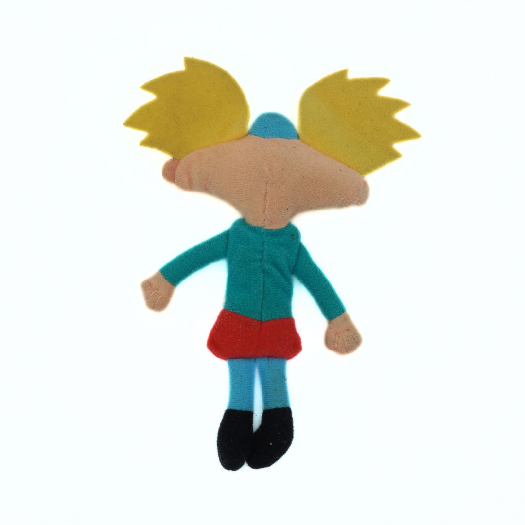 Toy figure with yellow hair, blue shirt, red skirt, and black shoes on a white background