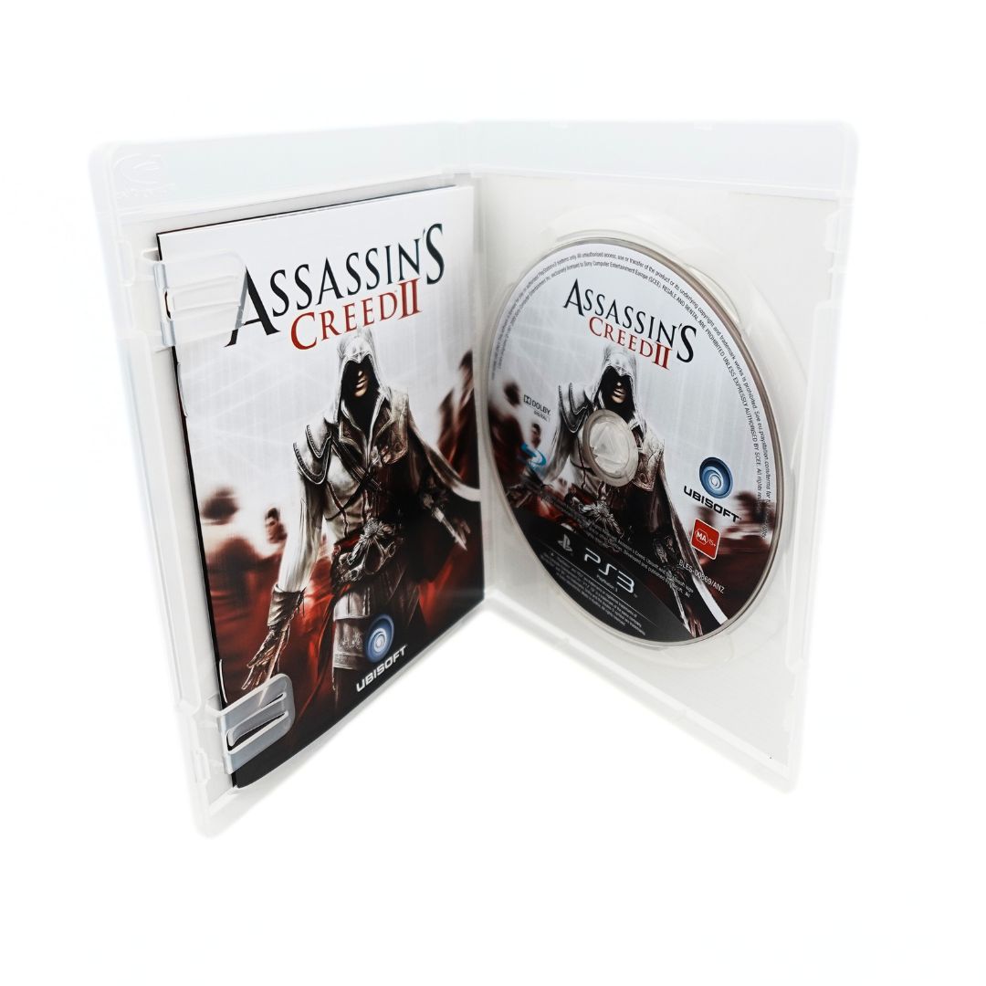 Inside of a 2009 Assassins Creed II game showing the disc and pamphlet 