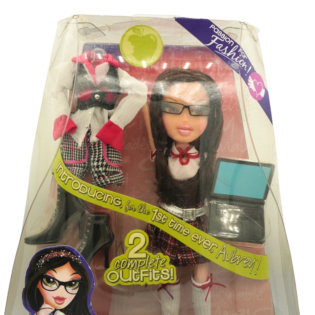 Bratz doll in its original clear plastic packaging, featuring a doll named Aubrey with long dark hair and sunglasses, complete with two outfits and a small black case.
