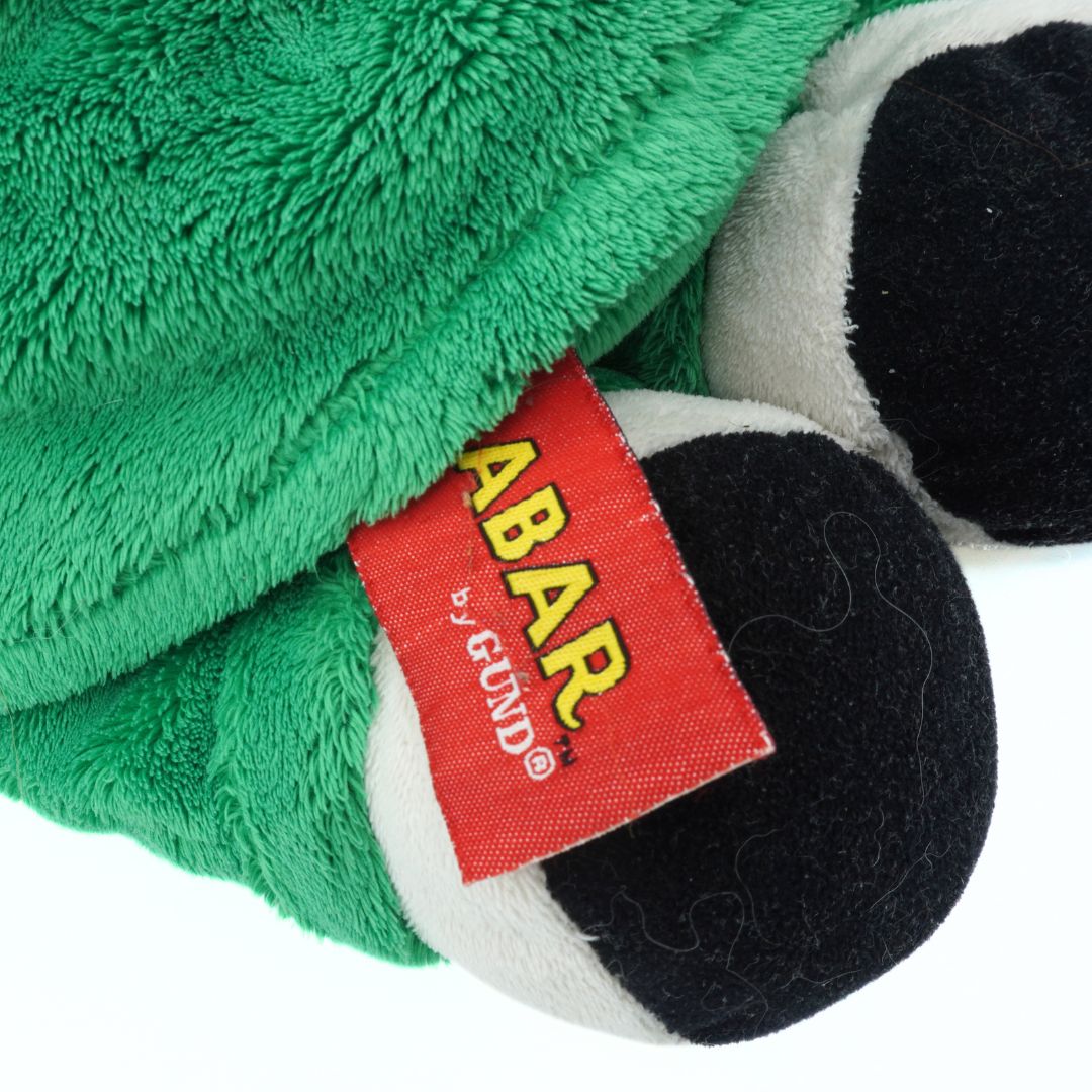 Close-up of a green plush toy with a red 'BABAR' label on a white background