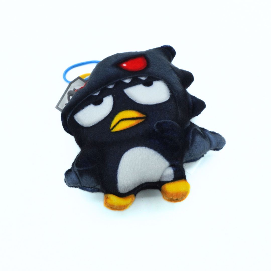 A black plush penguin toy with white belly, yellow beak and feet, wearing a red glowing eye hat, on a white background.