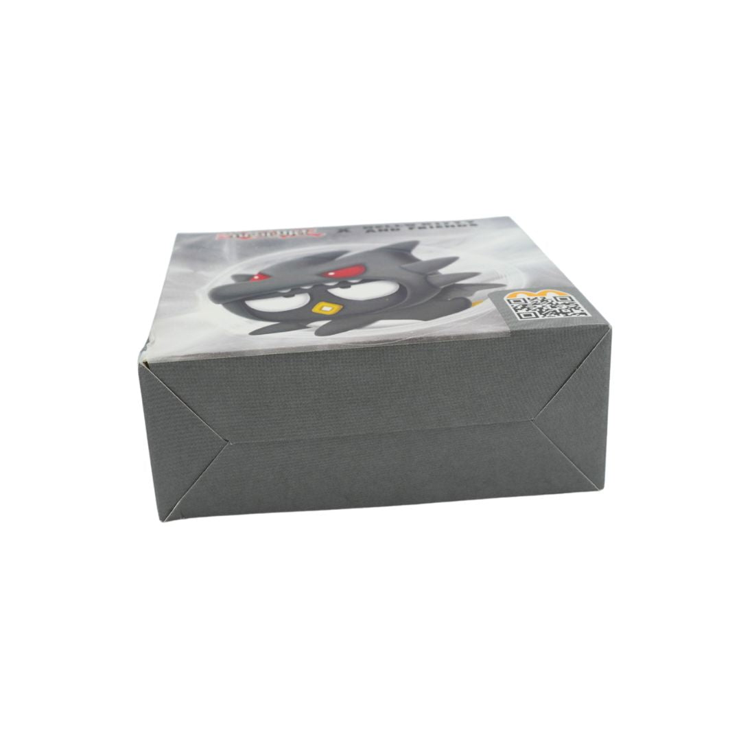 A square gray cardboard product box with a printed illustration of a black cartoon character with red eyes and a yellow star on a cloudy gray background. A QR code is visible on the top-right corner of the lid.