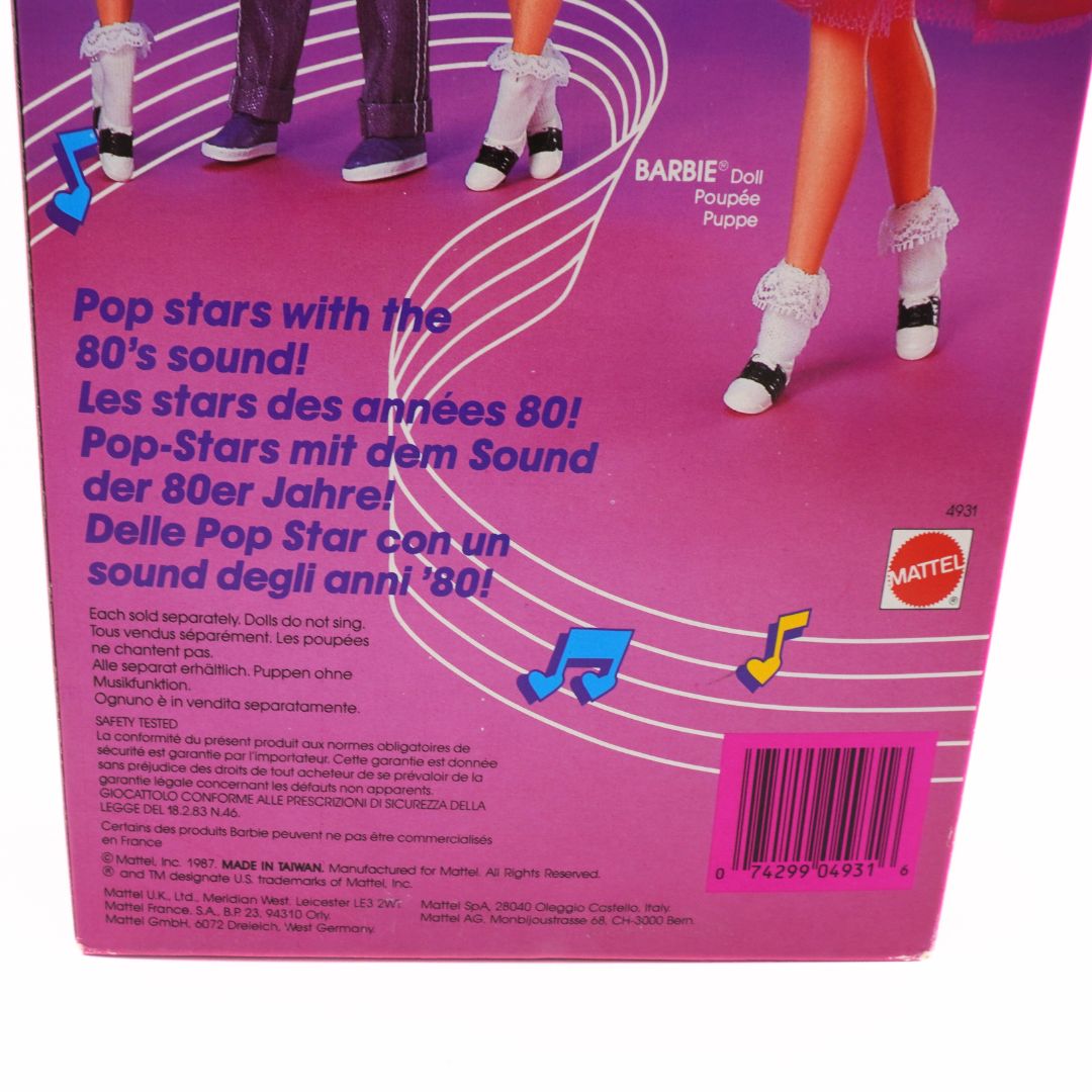 Back of a Barbie doll packaging with text and music notes, featuring Mattel branding.