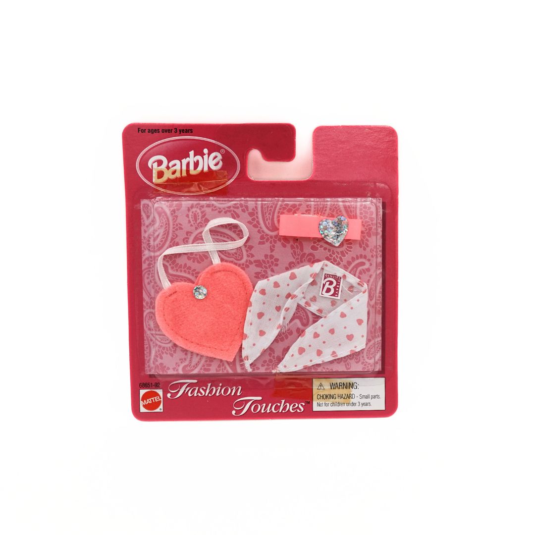 Photo of the front of a 90s Fashion Touches accessory set for Barbie with a pink heart shaped bag, white and pink scarf and pink and silver necklace