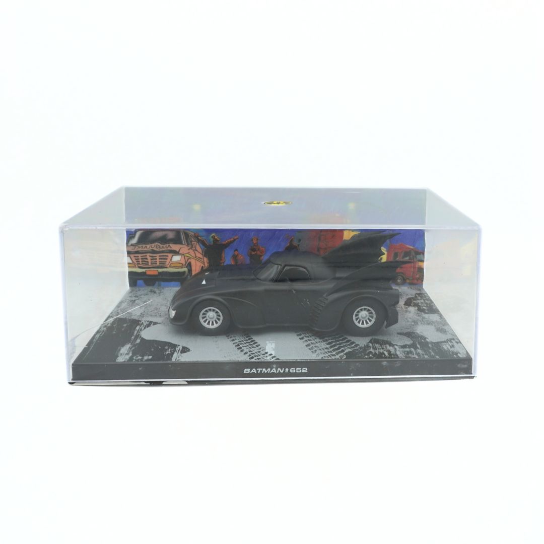 Model of a Batmobile in a display case with a cityscape background