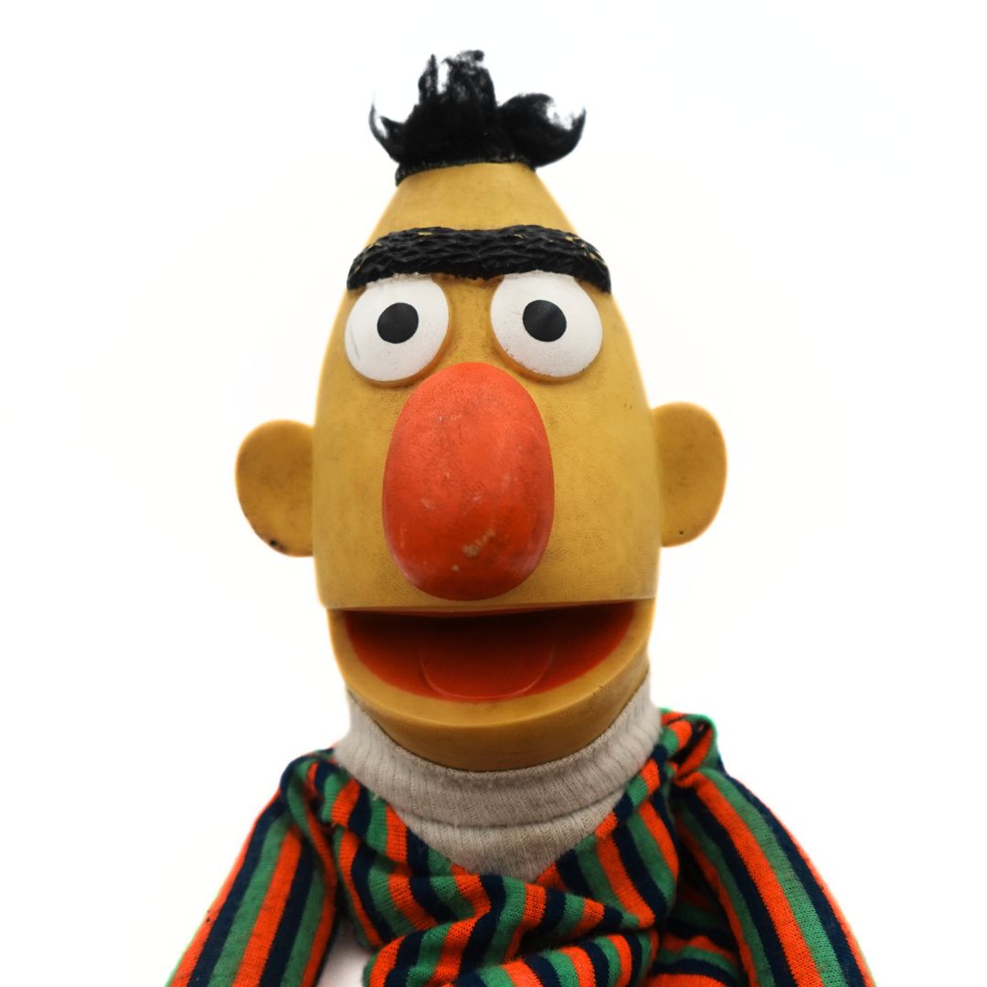 Photo of a vintage 1970's Sesame Street Puppet of Bert, wearing a striped shirt and with a yellow body