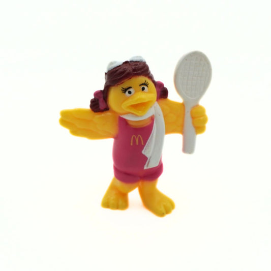A small yellow toy figure with a pink McDonald's outfit, white towel, and brown hair, holding a white tennis racket against a plain white background.